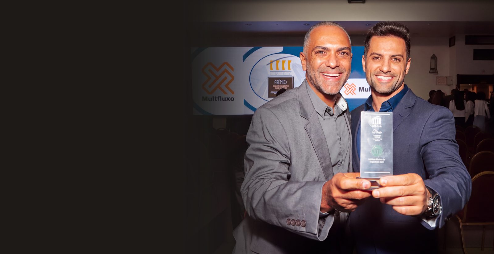 Dois sócios da Multfluxo seguram o troféu do 19º Prêmio Fornecedores Destaque da Construção Civil MG 2023, do Instituto Mineiro de Engenharia Civil (IMEC)